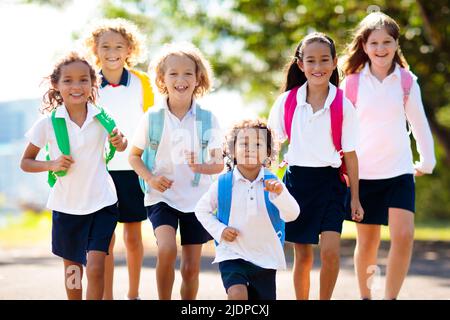 Die Kinder gehen zurück zur Schule. Interrassische Gruppe von Kindern unterschiedlichen Alters laufen und jubeln am ersten Tag des neuen akademischen Jahres. Beginn der Schulferien. Stockfoto