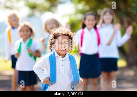 Die Kinder gehen zurück zur Schule. Interrassische Gruppe von Kindern unterschiedlichen Alters laufen und jubeln am ersten Tag des neuen akademischen Jahres. Beginn der Schulferien. Stockfoto