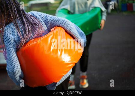 Helle Sportausrüstung für lustige Spiele. Mädchen zieht an sich. Tauziehen auf dem Spielplatz. Details zum Urlaub für jüngere Schüler. Stockfoto