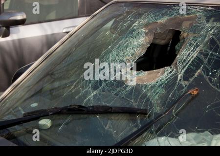 Gebrochene Windschutzscheibe mit Loch des Fahrzeugs, das in einen Unfall verwickelt ist. Stockfoto