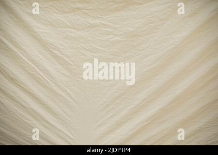 Weiße Markise mit Falten aus Spannung. Textur aus weißem Stoff. Gummimaterial. Zerknitterte Oberfläche. Stockfoto