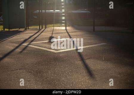 Zaun auf Sportplatz in Sonnenlicht. Stadiondetails. Sportplatz am Morgen. Morgendämmerung in der Stadt im Detail. Stockfoto