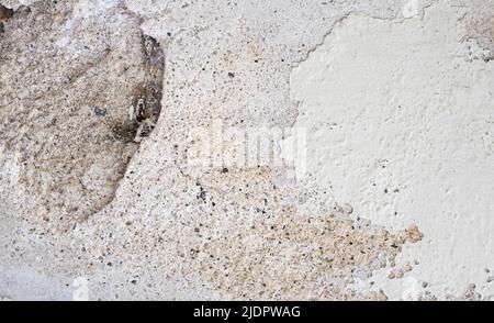 Nahaufnahme der verfallenen Wand mit abblätternder Farbe und Löchern auf dem Beton Stockfoto