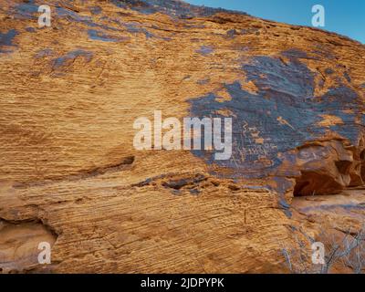 Petroglyphen, die durch Wüstenlack geschnitzt wurden, so dass das rote Gestein des Azteken-Sandsteins unten durch den Valley of Fire State Park, Nevada USA, leuchtet Stockfoto