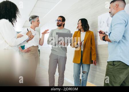 Multikulturelle Designprofis, die während eines Meetings in einem modernen Büro Ideen austauschen. Team aus innovativen Geschäftsleuten, die an einem neuen Kreativ zusammenarbeiten Stockfoto