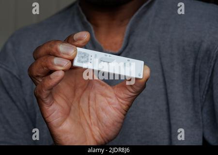 Person mit afrikanischer Ethnie, die einen einzigen positiven Covid-19-Schnelltest mit lateralem Flussantigen durchgeführt hat Stockfoto