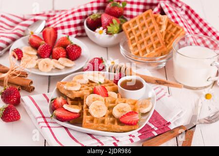 Waffeln mit Erdbeeren, Bananen und Honig. Stockfoto