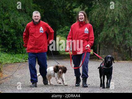 John Miskelly mit seinem Hund Bracken gemeinsam mit Teammitglied Emma Dryburgh und ihrem Hund Dougal führt John in seinem Haus in Falkland, Fife, ein spezialisiertes Hundeteam, das Leichen aufspüren und finden kann. Er und sein Team stehen bereit, um in der Ukraine zu helfen. Bilddatum: Dienstag, 21. Juni 2022. Stockfoto