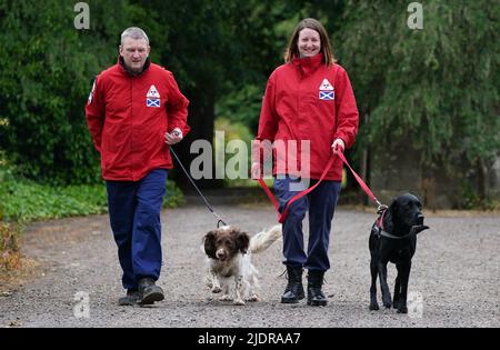 John Miskelly mit seinem Hund Bracken gemeinsam mit Teammitglied Emma Dryburgh und ihrem Hund Dougal führt John in seinem Haus in Falkland, Fife, ein spezialisiertes Hundeteam, das Leichen aufspüren und finden kann. Er und sein Team stehen bereit, um in der Ukraine zu helfen. Bilddatum: Dienstag, 21. Juni 2022. Stockfoto