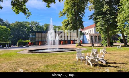 Brunnen im Kurpark, Hamm, Nordrhein-Westfalen, Deutschland. Theatergebäude und Kurhaus im Hintergrund. Stockfoto