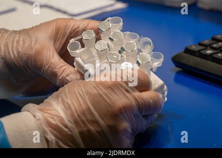 München, Deutschland. 23.. Juni 2022. Ein Mitarbeiter einer Apotheke in der Innenstadt hält ungenutzte Corona-Reagenzgläser. Kredit: Peter Kneffel/dpa/Alamy Live Nachrichten Stockfoto