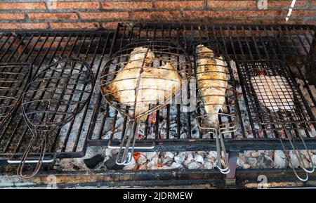 Frischer Fisch, der auf alten Kohleparrillas am Grill, weißer Fisch, Seebarsch und Steinbutt, außerhalb von Gebäuden im kleinen Fischerdorf Getaria, Baskisch, gebaut wird Stockfoto