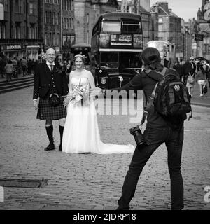 Ein frisch verheiratetes Paar, das Hochzeitsfotos auf der Royal Mile in Edinburgh in der Nähe des Edinburgh Castle gemacht hat Stockfoto