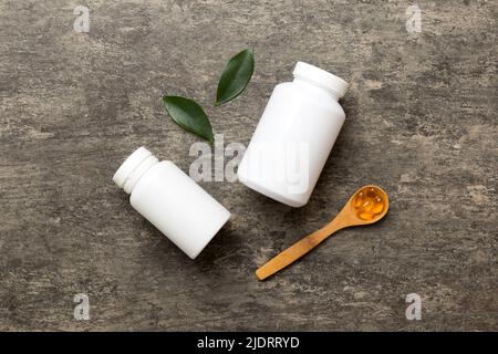 Omega-3 Kapseln liegen in einer weißen Flasche auf einem Tisch mit grünem Blatthintergrund. Fischöltabletten. Biologisch aktive Zusatzstoffe. omega 6, Omega 9, Vitam Stockfoto
