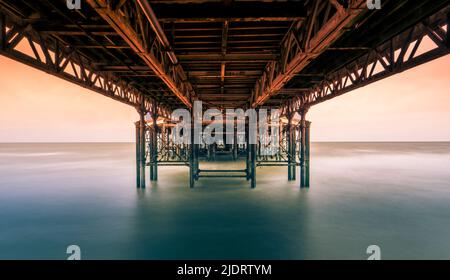 Langzeitbelichtung Fotografie fängt die Unterseite des Central Pier in Blackpool, Lancashire, Großbritannien bei Flut mit dem Meer sieht glatt und verschwommen Stockfoto