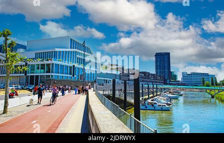 Venlo, Niederlande - Juni 9. 2021: Blick über Straße und Radweg auf die Skyline der modernen holländischen Stadt, Binnenhafen, Brücke, Uferpromenade Stockfoto