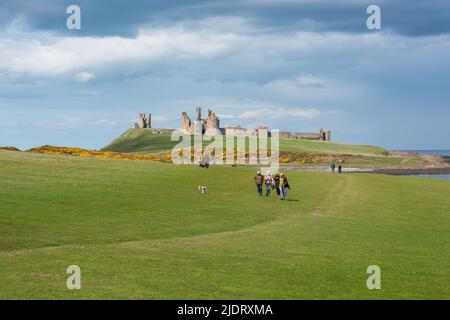 Senioren im Freien von Großbritannien, sehen Sie sich im späten Frühjahr eine Gruppe von Seniorenfreunden an, die den Northumberland Coast Path zwischen Craster und Dunstanburgh, Großbritannien, durchlaufen Stockfoto