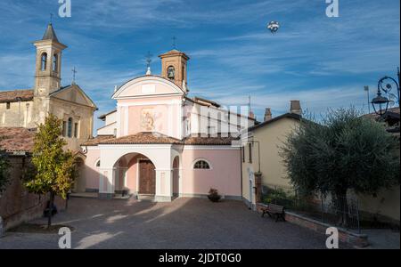 Die katholische Hauptkirche auf dem zentralen Platz von Barolo, Italien, mit einem Heißluftballon, der an einem Herbsttag in Piemonte, Italien, über dem Himmel fliegt Stockfoto