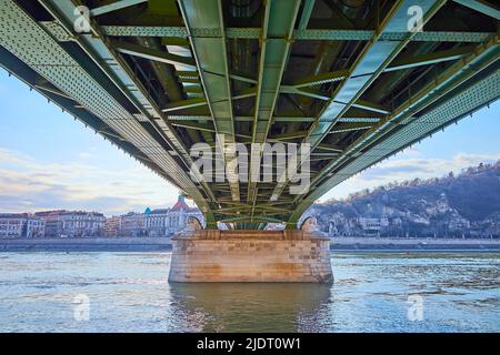 Der Blick unter der grünen Freiheitsbrücke auf den Gellert-Hügel, die Felskapelle am Fuße des Gellert-Thermalbads und des Hotelkomplexes, Budapest, Ungarn Stockfoto