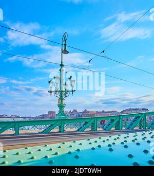 Die leuchtend grünen Metalldetails der Liberty Bridge mit Vintage-Lampenschirm im Hintergrund, Budapest, Ungarn Stockfoto