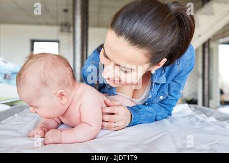 Glückliche Mutter und ihr neugeborenes Baby Wickelwindeln auf dem Wickeltisch Stockfoto