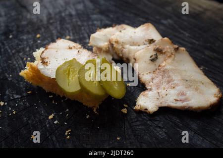 Appetitliche Scheiben becon und Sandwich liegen auf einem dunklen Küchentisch Stockfoto