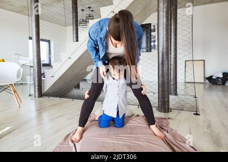 Mutter und Sohn spielen zusammen auf einer Decke zu Hause im Wohnzimmer Stockfoto