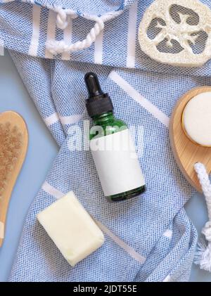 Green Dropper Flasche, Haut- und Haarpflegezubehör auf blauem Badetuch Draufsicht, Kopierraum. Verpackungsmodup. Natürliche hausgemachte Produkte Stockfoto