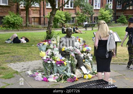 Manchester, Großbritannien. 23. Juni 2022. Blumensträuße, die am 23. Juni in Sackville Gardens, im Zentrum von Manchester, England, in der Alan Turing-Statue zum Geburtstag von Turing hinterlassen wurden. Turing gilt als der Vater der theoretischen Computerwissenschaft und künstlichen Intelligenz, spielte eine wichtige Rolle bei der Entwicklung von frühen Computern an der Universität Manchester und war ein berühmter Codebrecher aus dem Zweiten Weltkrieg. Die Wohltätigkeitsorganisation „Gleichstellungszeit“ übernimmt die Führung und hinterlässt Blumen an diesem Tag. Kredit: Terry Waller/Alamy Live News Stockfoto