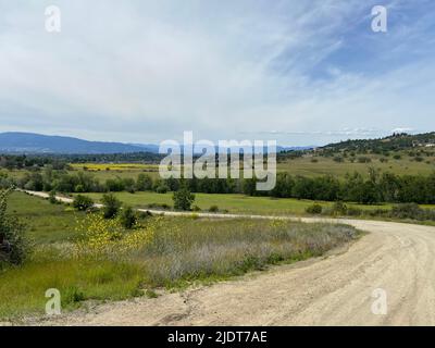 Kurvenreiche Feldstraße durch Wiesen und Felder in der Landschaft von Süd-Oregon, Pazifischer Nordwesten, USA. Stockfoto