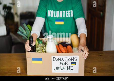 Volunteer bereitet Nahrungsmittelbox für Ukraine-Kriegsflüchtlinge vor - Fokus auf Hands Holding Box Stockfoto