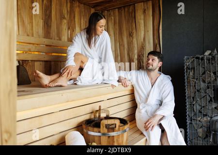 Glückliches junges Paar, das in der Sauna des Spa-Resorts ist Stockfoto