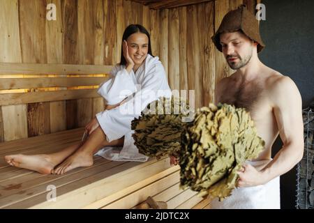 Fröhliches Paar, das sich während der Spa-Behandlungen in der Sauna entspannen kann Stockfoto