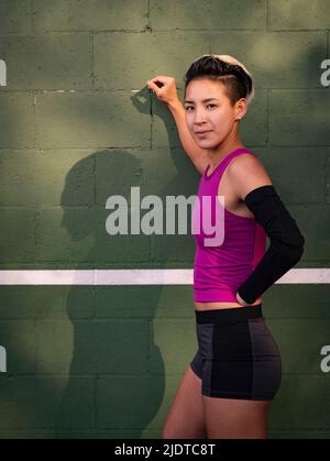 Porträt einer Sportlerin mit amputierter Hand, die gegen die Wand lehnt Stockfoto
