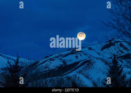 USA, Idaho, Bellevue, Vollmond über schneebedeckten Hügeln bei Nacht Stockfoto