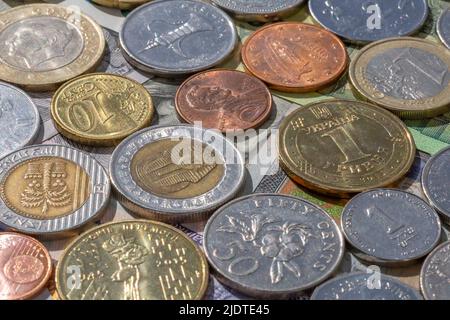 Nahaufnahme von Münzen verschiedener Währungen, die auf Papierbanknonten liegen Stockfoto