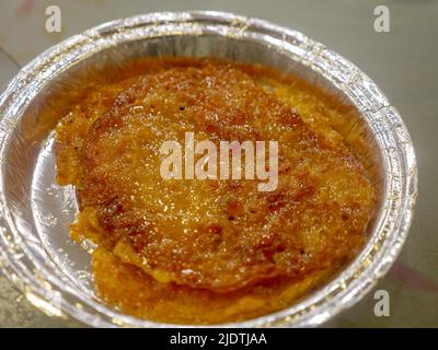 Malpua - traditioneller indischer süßer Pfannkuchen, überzogen mit Zuckersirup, der während Holi und Eid hergestellt wurde und bereit ist, in einem Süßgeschäft verkauft zu werden. Stockfoto