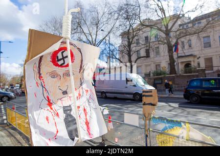 Plakate und Plakate gegen den russischen Präsidenten Wladimir Putin und seine Invasion in der Ukraine sind in der Nähe der russischen Botschaft in London zu sehen. Stockfoto