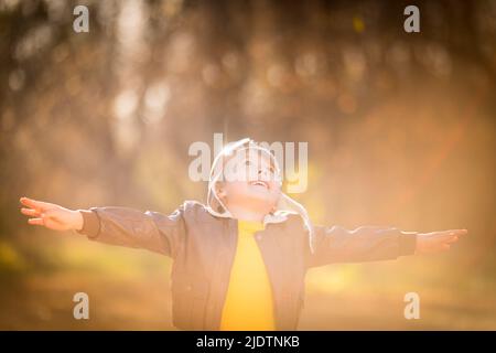 Porträt eines glücklichen Kindes mit Pilotenkostüm auf gelbem Hintergrund. Lächelndes Kind, das im Herbstpark Spaß hat. Freiheit und Phantasie Stockfoto