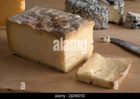 Ein Stück italienischen Taleggio-Käse und eine Scheibe auf einem Schneidebrett aus nächster Nähe Stockfoto
