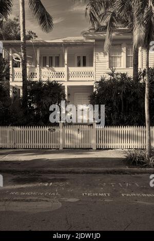 Wunderschönes Haus im Conch-Stil in der Altstadt in Key West, Florida, USA. Umgeben von einem weißen Zaun und Palmen. Starker Kontrast. Stockfoto