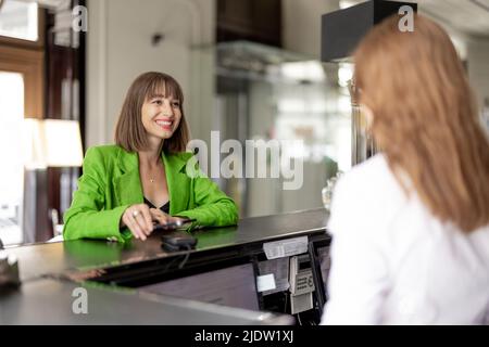 Geschäftsfrau zahlt an der Hotelrezeption Stockfoto