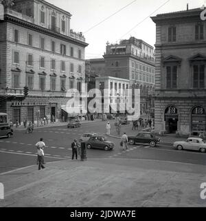 1950s, historisch, Straßenszene, Stadtzentrum, Neapel, Italien. Auf dem Bild sind eine Gelateria, ein Misano-Supermarkt, eine Banco di Napoli und ein italienischer Verkehrspolizist in einem weißen Anzug mit Helm auf dem Bürgersteig an einer Ecke der Kreuzung zu sehen. Stockfoto