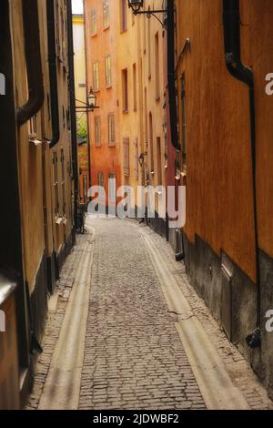 Ruhige, leere gepflasterte Straße in einer kleinen europäischen Touristenstadt. Eine schmale Gasse in einer ländlichen Stadt, umgeben von hohen Mehrfamilienhäusern oder roten Häusern Stockfoto