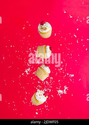 Viele kleine appetitliche Muffins mit Rahm und frischen Beeren auf einem rosa Hintergrund in einem gefrorenen Flug. Festliche Komposition. Urlaubseinladung, Geburtstag, Stockfoto