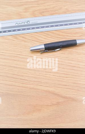 Dezimallineal aus Metall und Bleistift auf einem Holzschreibtisch Stockfoto