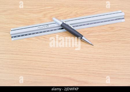 Dezimallineal aus Metall und Bleistift auf einem Holzschreibtisch Stockfoto