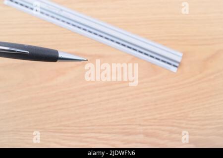 Dezimallineal aus Metall und Bleistift auf einem Holzschreibtisch Stockfoto