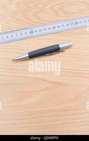 Dezimallineal aus Metall und Bleistift auf einem Holzschreibtisch Stockfoto