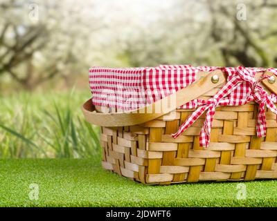 Sommer Erholung im Freien, Picknick. Vor der Kulisse der schönen Natur, grünes Gras, ein Strohpicknickkorb. Ruhe, Picknick. Es sind keine Personen drin Stockfoto